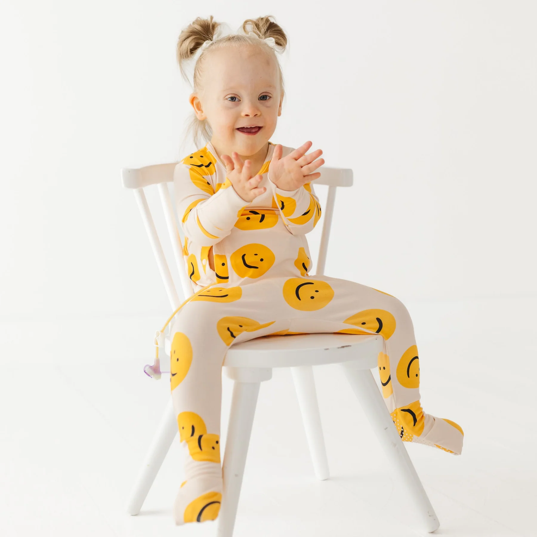 Toddler girl sits on a chair wearing nighttime romper with toes